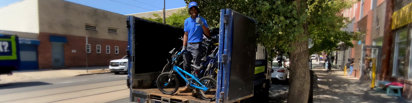 1-800-GOT-JUNK? team member putting bicycle in back of truck for bicycle recycling